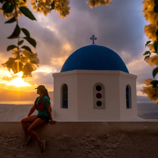 Woman sat on wall with white and blue building behind her