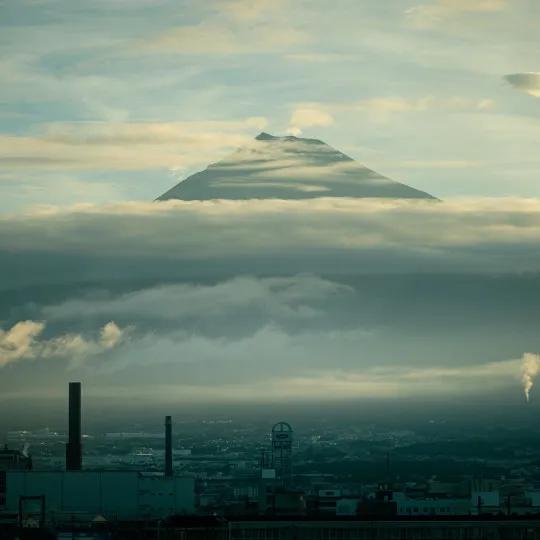 City below and Mount Fuji poking through clouds in the background