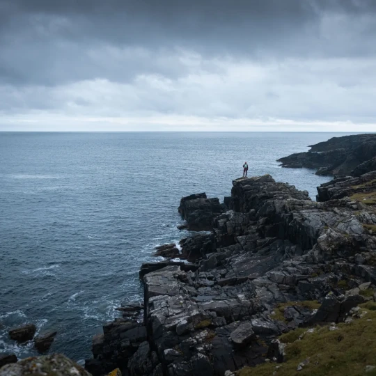 Person stood on rocks, looking out to sea
