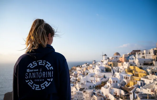 Woman wearing Santorini hoodie and looking down onto white buildings