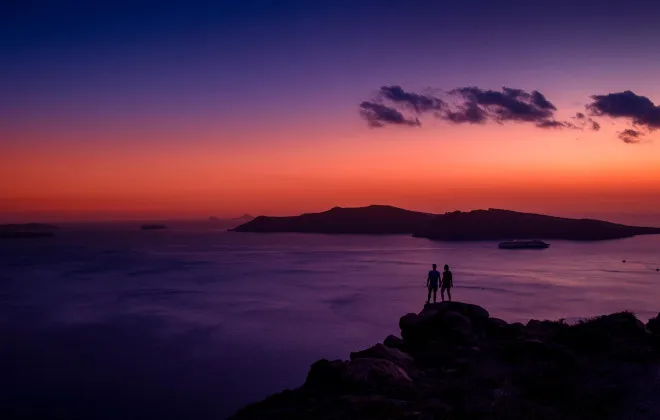 Participants stood on rocks and watching colourful sunset