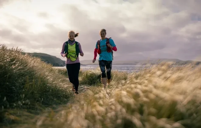 Women running along grassy coastline