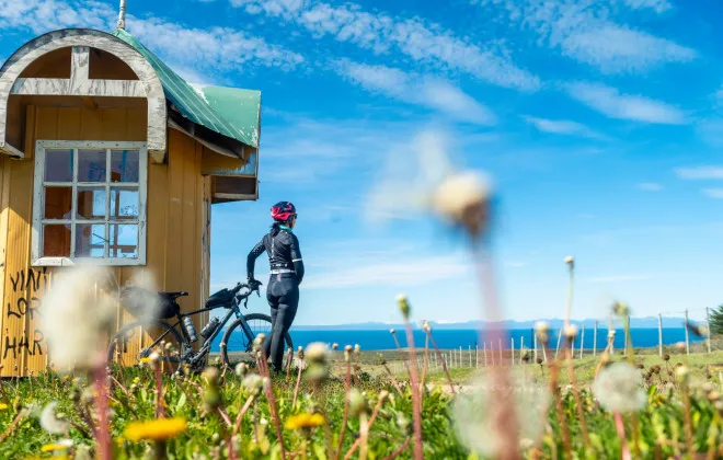 Woman stood with bike, looking out to water