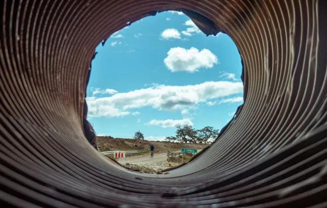 View through pipe of cyclist riding on road