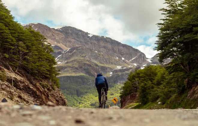 Cyclist riding along road, towards mountains