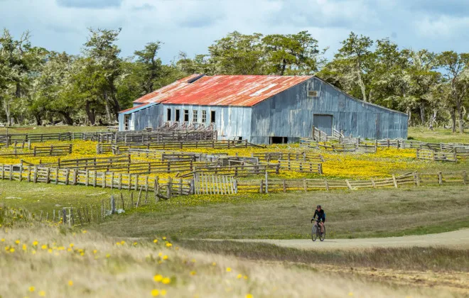 Cyclist riding past barn and farmland