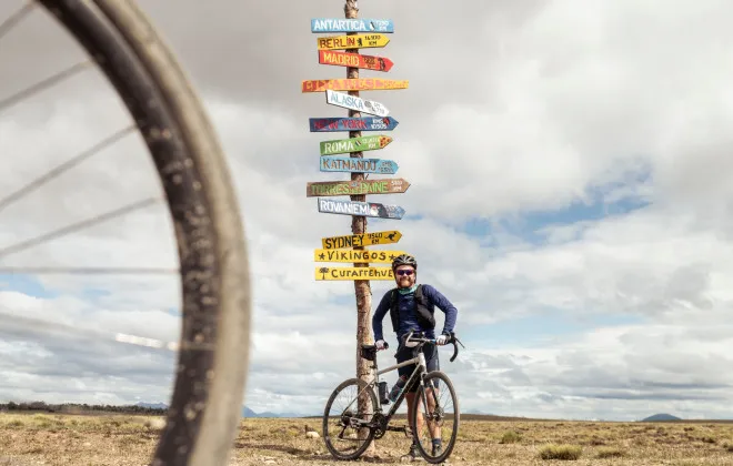 Man stood infront of signs pointing to different places