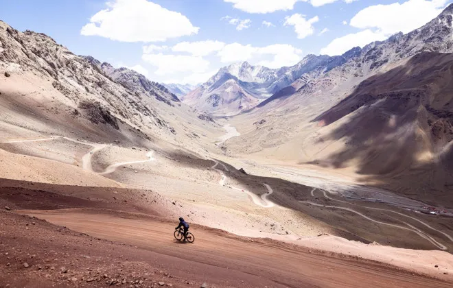Cyclist riding along rocky path next to mountains
