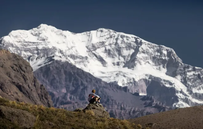 Participant sat on rock, looking up at snow-covered mountain