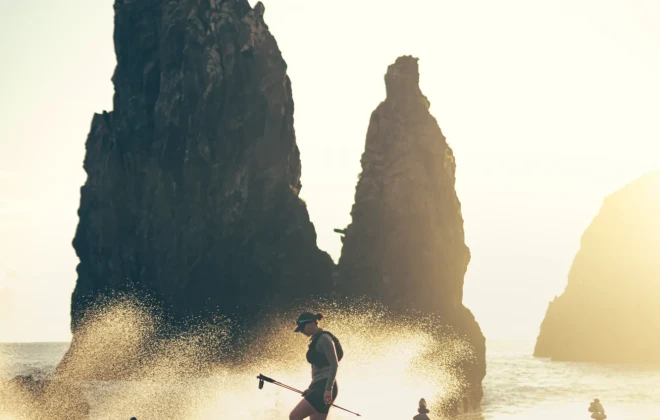 Participants running over round rocks and sea crashing against them