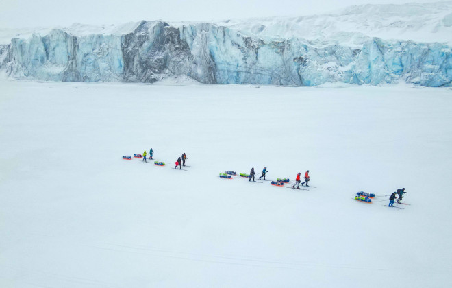 Participants pulling sleds through snowy terrain