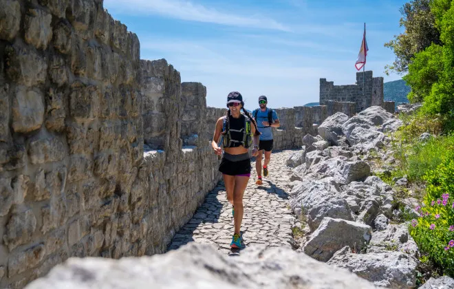 A man and a woman run next to a wall