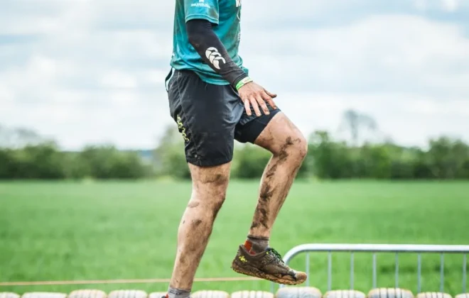 Mud-covered man walking along tyres