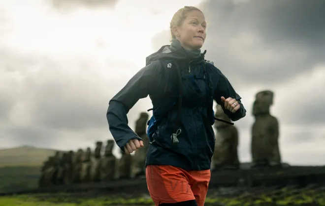 Woman running past a wall of statues