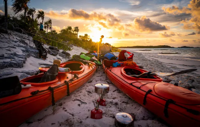 Kayaks placed on a sandy beach next to the water