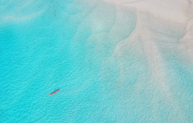 Aerial view of kayak moving through clear, shallow water