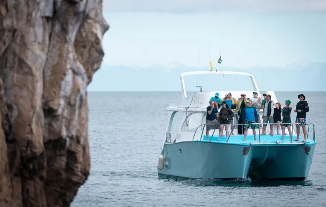 Participants stood on boat, looking at rock