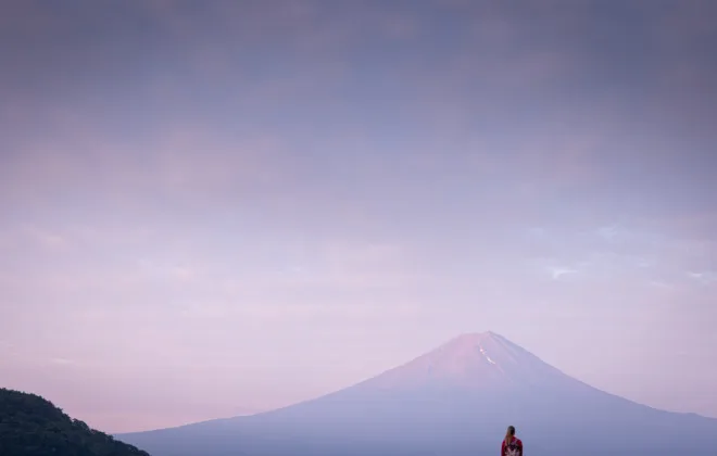 Woman stood infront of Mount Fuji with a colourful sky above