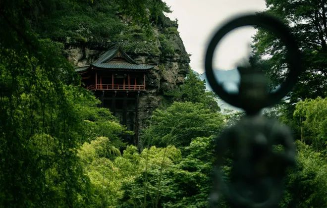 Traditional Japanese building attached to cliff and surrounded by greenery