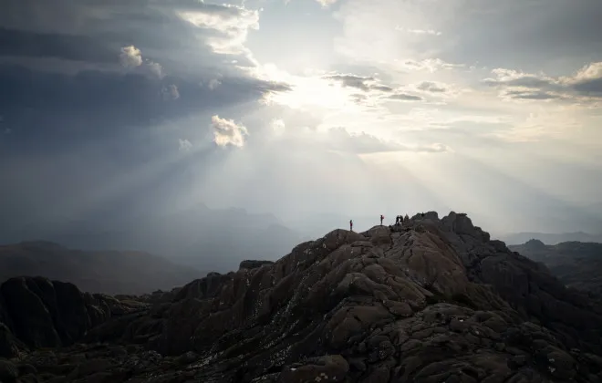 Participants standing on rocky mountains with blue sky above them