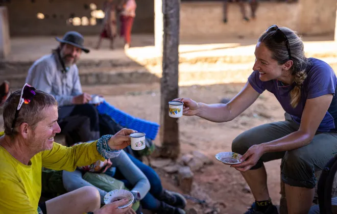 Man and woman laughing and drinking from small cups and saucers