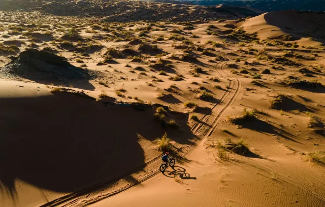 Cyclist riding over sandy and grassy path