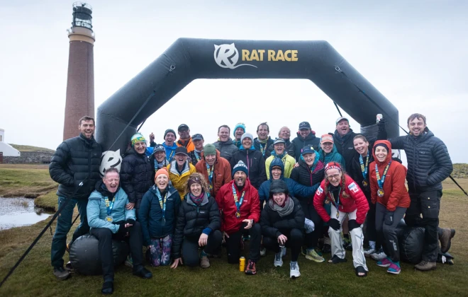 Participants smiling beneath Rat Race arch