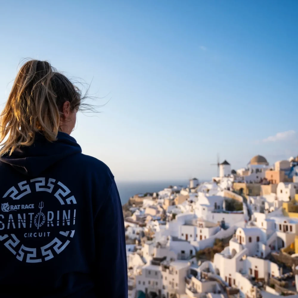 Woman wearing Santorini hoodie and looking down onto white buildings