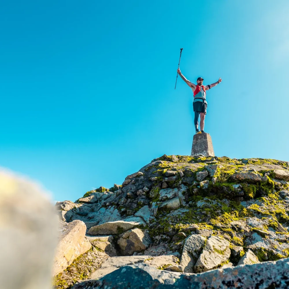Man stood on trig point at top of Ben Nevis